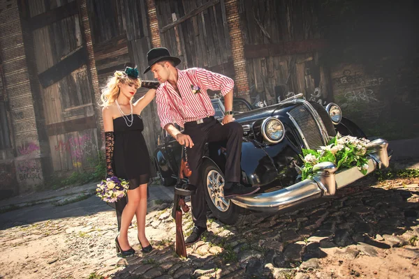 Casal em chapéus perto de carro à moda antiga — Fotografia de Stock