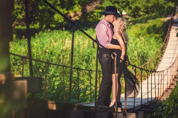 Couple kissing on a wooden bridge — Stock Photo, Image