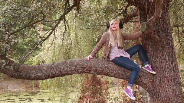 Attractive young woman on big old tree — Stock Video