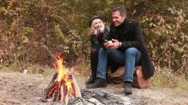 Paar trinkt Tee oder Kaffee am Feuer — Stockvideo