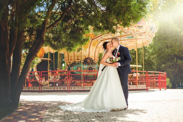 Bruidegom en de bruid in de buurt van carrousel — Stockfoto