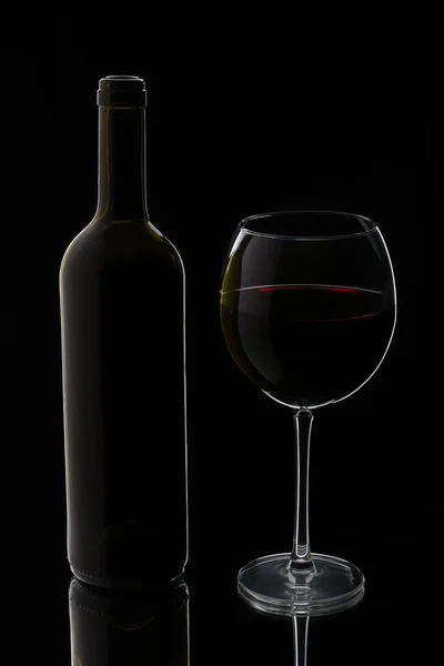 Glas rött vin med flaska — Stockfoto