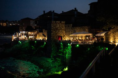 Bulgaristan 'ın Sozopol kentindeki antik duvarın gece görüntüsü. Yemek hazırlayan insanlar var.