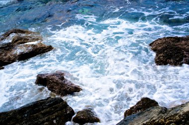 Mavi deniz suyu, dalgalar ve taşlar