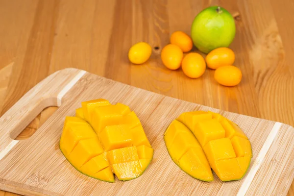 Taze Kumquats ve ahşap bir masa üzerinde bir kireç ile kesme tahtası üzerinde taze mango — Stok fotoğraf