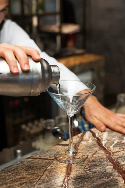 Barman w pracy, przygotowywanie koktajli. odlewania martini do kieliszka koktajlowego. — Zdjęcie stockowe