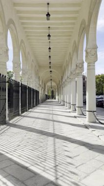 MADRID, SPAIN - NOVEMBER 02, 2025: Uzun taş sütun boyunca ilerleyen sinematik yavaş zoom çekimi ve tarihi Cementerio de la Almudena 'nın ana girişindeki kemerler. Yüksek karşıtlık gölgeleri ve perspektif.