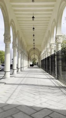 MADRID, SPAIN - NOVEMBER 02, 2025: Uzun taş sütun boyunca ilerleyen sinematik yavaş zoom çekimi ve tarihi Cementerio de la Almudena 'nın ana girişindeki kemerler. Yüksek karşıtlık gölgeleri ve perspektif.