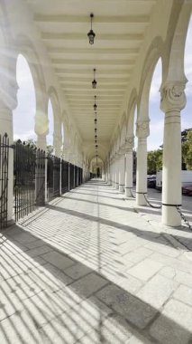 MADRID, SPAIN - NOVEMBER 02, 2025: Uzun taş sütun boyunca ilerleyen sinematik yavaş zoom çekimi ve tarihi Cementerio de la Almudena 'nın ana girişindeki kemerler. Yüksek karşıtlık gölgeleri ve perspektif.