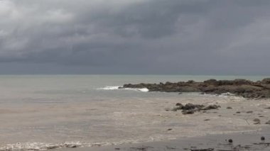 Deniz duvarı ve bulutlu ve yağmurlu bir gökyüzü stoğu olan bir fırtınadan sonra kumlu okyanus. 