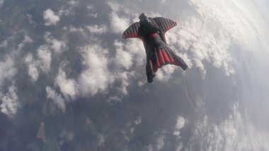 Wingsuit skydiving over clouds clipart