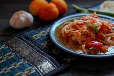 Baharatlı papaya salatası mavi bir tabakta, kovada pilav ve uzun fasulye, kurutulmuş kırmızı biber ve sebze ile servis edilir..