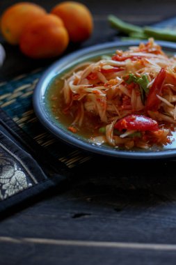 Baharatlı papaya salatası mavi bir tabakta, kovada pilav ve uzun fasulye, kurutulmuş kırmızı biber ve sebze ile servis edilir..