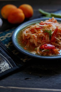 Baharatlı papaya salatası mavi bir tabakta, kovada pilav ve uzun fasulye, kurutulmuş kırmızı biber ve sebze ile servis edilir..