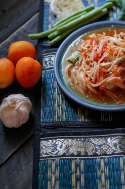Baharatlı papaya salatası mavi bir tabakta, kovada pilav ve uzun fasulye, kurutulmuş kırmızı biber ve sebze ile servis edilir..