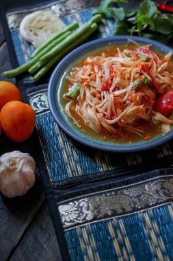 Baharatlı papaya salatası mavi bir tabakta, kovada pilav ve uzun fasulye, kurutulmuş kırmızı biber ve sebze ile servis edilir..
