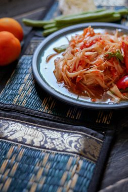 Baharatlı papaya salatası mavi bir tabakta, kovada pilav ve uzun fasulye, kurutulmuş kırmızı biber ve sebze ile servis edilir..