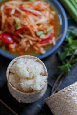 Baharatlı papaya salatası mavi bir tabakta, kovada pilav ve uzun fasulye, kurutulmuş kırmızı biber ve sebze ile servis edilir..