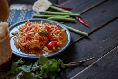 Baharatlı papaya salatası mavi bir tabakta, kovada pilav ve uzun fasulye, kurutulmuş kırmızı biber ve sebze ile servis edilir..