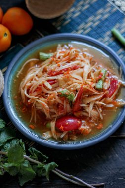 Baharatlı papaya salatası mavi bir tabakta, kovada pilav ve uzun fasulye, kurutulmuş kırmızı biber ve sebze ile servis edilir..