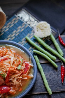 Baharatlı papaya salatası mavi bir tabakta, kovada pilav ve uzun fasulye, kurutulmuş kırmızı biber ve sebze ile servis edilir..