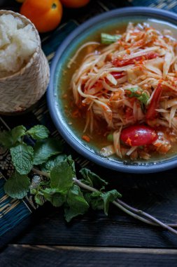 Baharatlı papaya salatası mavi bir tabakta, kovada pilav ve uzun fasulye, kurutulmuş kırmızı biber ve sebze ile servis edilir..