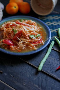 Baharatlı papaya salatası mavi bir tabakta, kovada pilav ve uzun fasulye, kurutulmuş kırmızı biber ve sebze ile servis edilir..