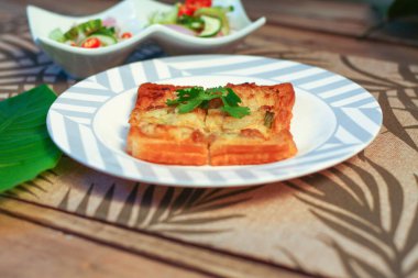 Tahta masaya salatalık sosu serpiştirilmiş kıymalı kızarmış ekmek. Ya da bizim deyimimizle 