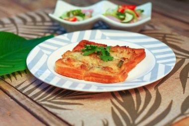 Tahta masaya salatalık sosu serpiştirilmiş kıymalı kızarmış ekmek. Ya da bizim deyimimizle 