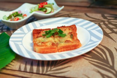 Tahta masaya salatalık sosu serpiştirilmiş kıymalı kızarmış ekmek. Ya da bizim deyimimizle 