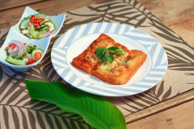 Tahta masaya salatalık sosu serpiştirilmiş kıymalı kızarmış ekmek. Ya da bizim deyimimizle 