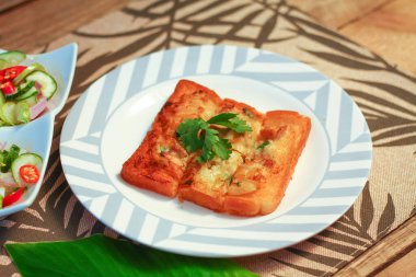 Tahta masaya salatalık sosu serpiştirilmiş kıymalı kızarmış ekmek. Ya da bizim deyimimizle 