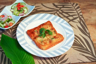 Tahta masaya salatalık sosu serpiştirilmiş kıymalı kızarmış ekmek. Ya da bizim deyimimizle 