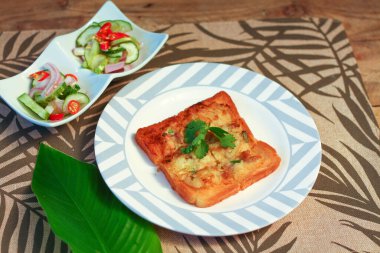 Tahta masaya salatalık sosu serpiştirilmiş kıymalı kızarmış ekmek. Ya da bizim deyimimizle 