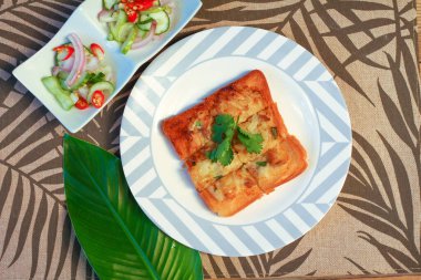 Tahta masaya salatalık sosu serpiştirilmiş kıymalı kızarmış ekmek. Ya da bizim deyimimizle 