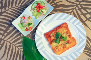 Tahta masaya salatalık sosu serpiştirilmiş kıymalı kızarmış ekmek. Ya da bizim deyimimizle 