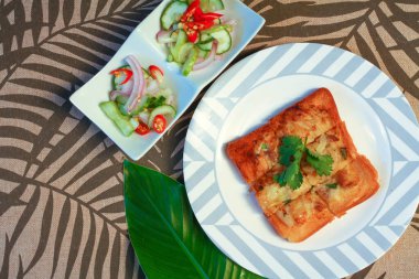 Tahta masaya salatalık sosu serpiştirilmiş kıymalı kızarmış ekmek. Ya da bizim deyimimizle 