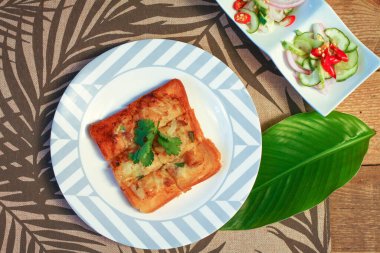 Tahta masaya salatalık sosu serpiştirilmiş kıymalı kızarmış ekmek. Ya da bizim deyimimizle 