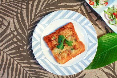 Tahta masaya salatalık sosu serpiştirilmiş kıymalı kızarmış ekmek. Ya da bizim deyimimizle 