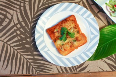 Tahta masaya salatalık sosu serpiştirilmiş kıymalı kızarmış ekmek. Ya da bizim deyimimizle 