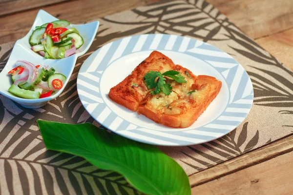 Tahta masaya salatalık sosu serpiştirilmiş kıymalı kızarmış ekmek. Ya da bizim deyimimizle 