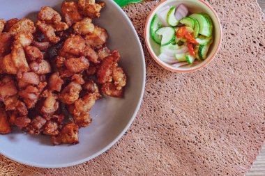 Balık soslu kızarmış domuz eti ve siyah ahşap zeminde beyaz tabakta servis edilen yapışkan pirinç..