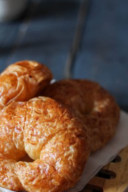 Kruvasan, siyah ahşap bir masada kahve ile servis edilir..