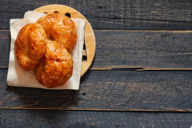 Kruvasan, siyah ahşap bir masada kahve ile servis edilir..