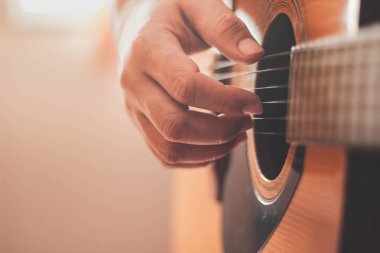 Gitarist yan ışıklandırmalı bir odada gitar çalıyor..