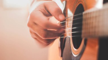 Gitarist yan ışıklandırmalı bir odada gitar çalıyor..