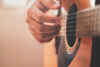 Gitarist yan ışıklandırmalı bir odada gitar çalıyor..