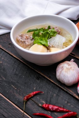 Kaynamış tofu ve kıymalı domuz eti, siyah ahşap masada servis edilen beyaz bardaklarda servis edilir..