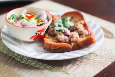 Tahta masaya salatalık sosu serpiştirilmiş kıymalı kızarmış ekmek. Ya da bizim deyimimizle 