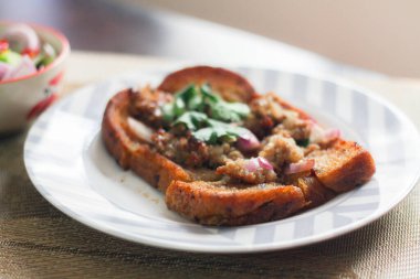 Tahta masaya salatalık sosu serpiştirilmiş kıymalı kızarmış ekmek. Ya da bizim deyimimizle 